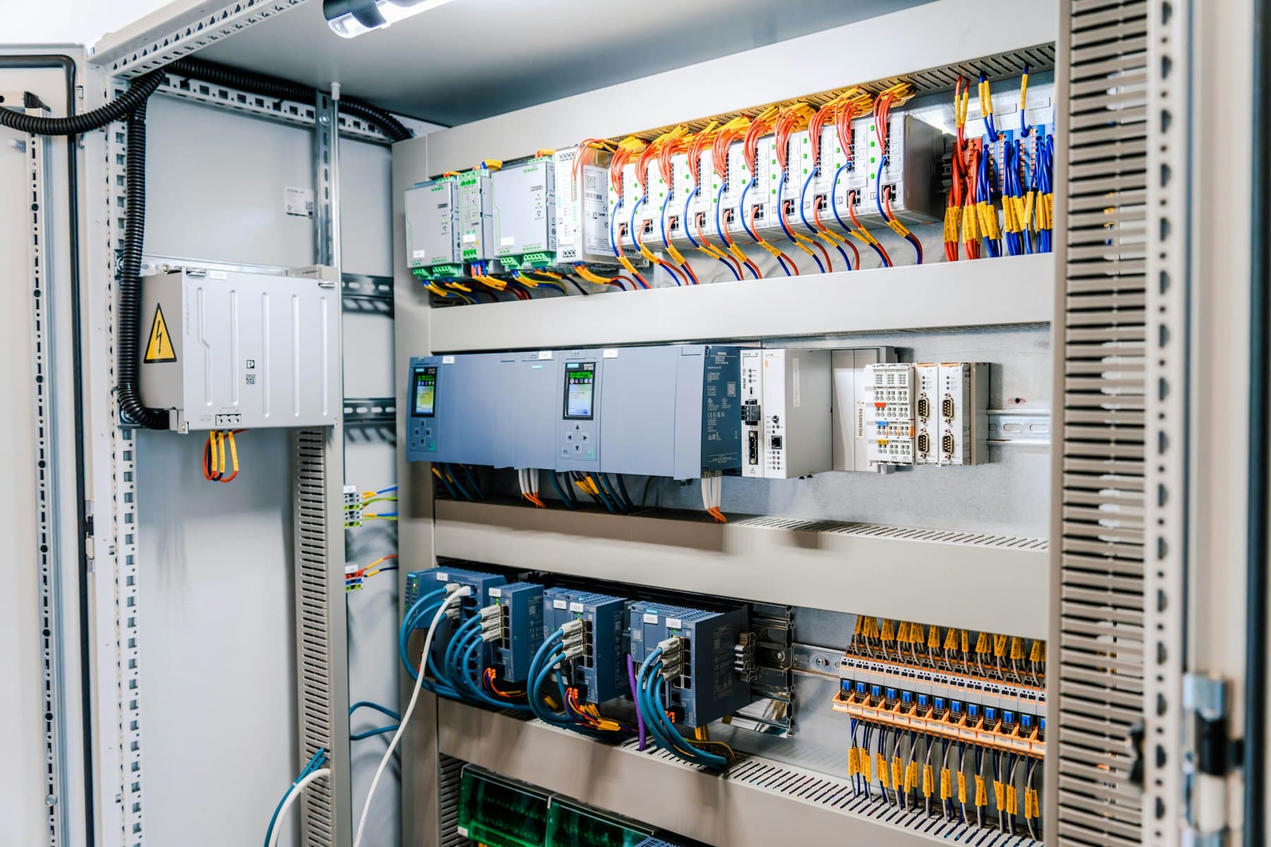 Open control cabinet with PLC, I/O and drive modules on DIN rail.